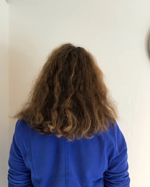 Achteraanzicht van schouderlang golvend haar vóór de CC1-knipbehandeling.